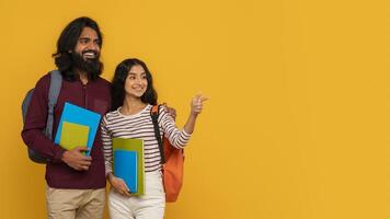 Two students holding books on yellow background photo