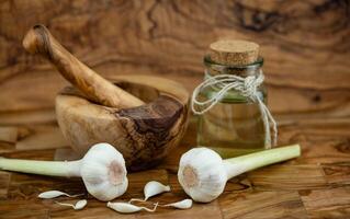 Fresco ajo para aceite de ajo en aceituna madera foto