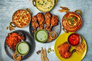 Chicken Tikka Butter Masala, Reshmi masala, Ginger Chicken, Tangri Kabab, Lal Badsha, tandoori, Peri peri, with chili sauce served in a dish isolated on grey background top view of bangladesh food photo