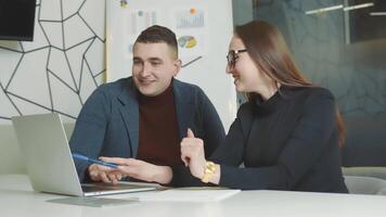 Mens en vrouw werken samen in de kantoor. gelukkig mensen glimlachen Bij werk en Bij werk in de kantoor. gebaard Mens en vrouw met rood haar- van Kaukasisch nationaliteit. video