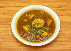 aloo anday shorba or egg potato curry served in plate isolated on table top view of indian and pakistani spicy food photo