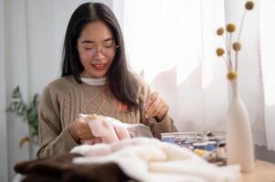 A focused young Asian woman threading a pattern on an embroidery frame, hand-sewing on cloth. photo