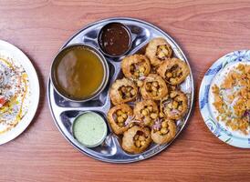 channa papri charla condimento, dahi baray y pani puri o gol pago por brecha con raita, dulce salsa y picante agua servido en plato aislado en mesa parte superior ver de indio y pakistaní comida foto