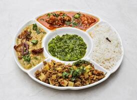 sindhi non vegetable thali with aloo keema, chicken korma, curry pakora, rice and chutney served in plate isolated on table top view of indian and pakistani spicy food photo