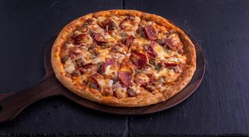 Hot meat pizza isolated on cutting board top view on dark background italian fast food photo