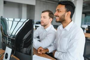 Two men traders sitting at desk at office together monitoring stocks data candle charts on screen analyzing price flow smiling cheerful having profit teamwork concept photo