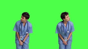 Medical assistant being impatient against greenscreen backdrop, looking around and waiting for patients at consultations. Nurse with health expertise feeling frustrated while she waits. Camera B. video