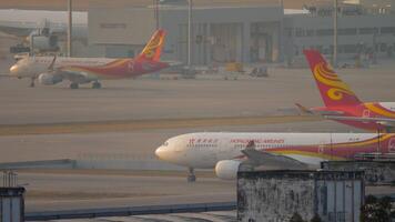 HONG KONG - NOVEMBER 07, 2019. Passenger plane Airbus A330, B-LNI of Hong Kong Airlines taxiing at Hong Kong airport. Airplane in sunlight at sunset or dawn video