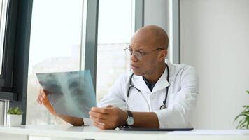 joven africano americano masculino médico trabajando con el radiografía a escritorio video