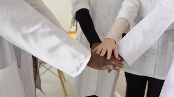 A team of doctors, including women and men of different nationalities, make a gesture of unity. Close-up shooting of hands video