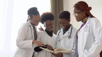 africano médico estudiantes con libros son que se discute alguna cosa en un hospital. grupo de joven africano americano doctores a el clínica video