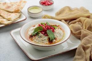 Mutabal with pomegranate seeds and bread served in dish isolated on table top view of arabian food photo