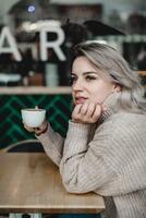 Cafe Contemplation. Woman Lost in Thought with Coffee - Serene Moment of Reflection at Cafe Table - Cozy Ambiance with Sweater-Clad Woman in Quiet Contemplation photo