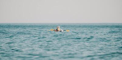 contento Pareja kayaks en un inflable kayac en el mar a puesta de sol. Pareja piragüismo en el mar cerca el isla con montañas. personas kayak en vida chaquetas navegar. espalda ver foto