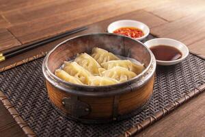 Bamboo Steamed Pork Dumplings with sauce served dish isolated on wooden table top view of Hong Kong food photo