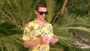 Man counting Thai Baht on a beach with palm leaves in the background video