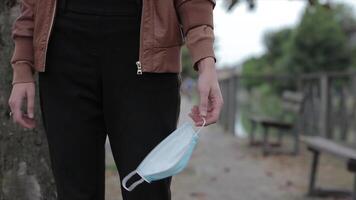 detalhe do uma garotas mão segurando uma médico mascarar enquanto caminhando 3 video