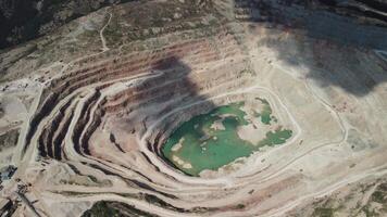 Aerial view industrial of opencast mining quarry with lots of machinery at work - extracting fluxes for the metal industry. Oval mining industrial crater, acid mine drainage in rock. video