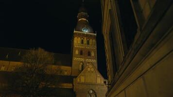 een middeleeuws toren is verlichte Bij middernacht in voorkant van een groots gebouw video