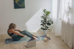 A 50-year-old woman doing online yoga at home photo