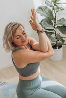 A 50-year-old woman does yoga at home photo