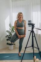 A 50-year-old woman doing online yoga at home photo