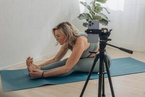 A 50-year-old woman doing online yoga at home photo