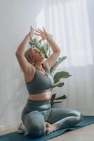 A 50-year-old woman does yoga at home photo
