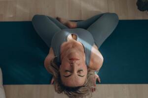 A 50-year-old woman does yoga at home photo