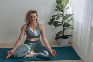 A 50-year-old woman does yoga at home photo