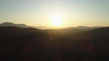 aéreo ver de hermosa enorme verde montañas debajo el puesta de sol cielo. disparo. muchos colinas cubierto por verde arboles en claro puesta de sol cielo antecedentes. video