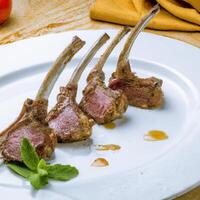 AI generated Fresh rack of lamb, carre  dagneau, on a white plate with herbs, rosemary, basil and sauces. Side view, close up. AI generated. photo