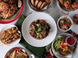 selective choice food table Shell Crab noodle , Chicken Satay, Spring Roll, Curry Samosa, fish cake, Folks Drumlet, Pork Jar Salad in a dish isolated on mat top view on grey marble background photo