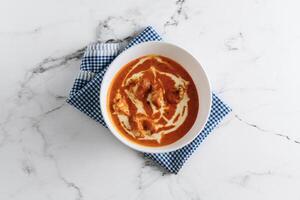 Traditional indian food Murgh Makhani or Butter chicken, tikka masala in a dish isolated on napkin side view on grey background photo