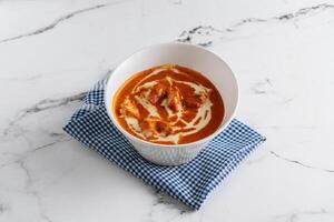 Traditional indian food Murgh Makhani or Butter chicken, tikka masala in a dish isolated on napkin side view on grey background photo