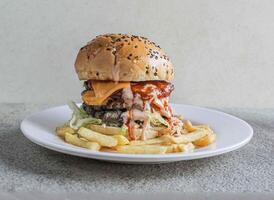 Double beef cheese burger with fries served in a dish isolated on grey background side view of fast food photo
