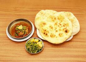 Spicy chicken korma khamiri roti, lemon slice and salad served in a dish isolated on wooden table side view of indian, pakistani food photo