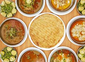 Assorted pakistani food chicken or beef nali nihari, maghaz, brain, chicken korma, with naan, sheermal taftan ginger and lemon slice salad served isolated on table top view of indian food photo