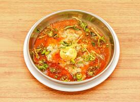 Maghaz or brain nihari with lemon and ginger slice served in a dish isolated on wooden table side view of indian, pakistani food photo