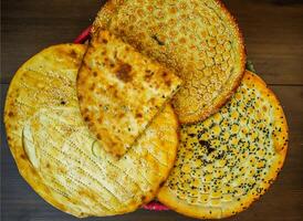 Assortment of breads Tandoori paratha, aloo naan, special roghni, kalonji naan, served in basket isolated on table top view of india and pakistani food photo