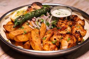 Shish tawook or tawooq with salad, wedges, lemon and dip served in dish isolated on background top view of arabic food photo