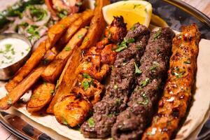 Assorted mix grills with chicken tikka, beef kabab, mutton kebab, wings, boti, malai, shish tawook served in dish isolated on background top view of arabic food photo