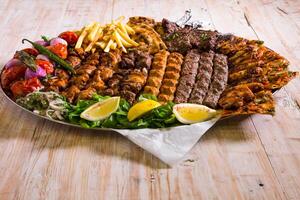 Assorted mix grills with chicken tikka, beef kabab, mutton kebab, wings, boti, malai, chop, shish tawook served in dish isolated on background top view of arabic food photo