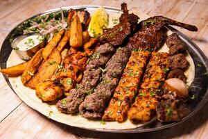 Assorted mix grills with chicken tikka, beef kabab, mutton kebab, wings, boti, malai, chop, shish tawook served in dish isolated on background top view of arabic food photo