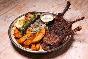 Riyash lamb chop with salad, wedges, lemon and dip served in dish isolated on background top view of arabic food photo