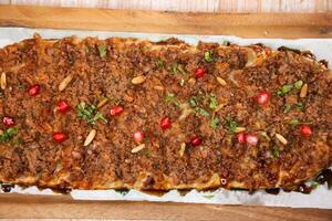 Lahm bi ajeen pizza bread served in wooden board isolated on background top view of Arabic Manaqeesh photo