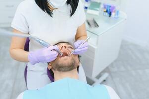 hombre teniendo un visitar a el del dentista. hermoso paciente sentado en silla a dentista oficina en dental clínica. foto