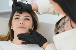 cosmetóloga aplicando permanente hacer arriba en Cejas- ceja tatuaje foto