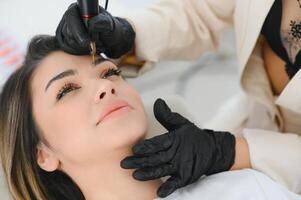 Cosmetologist applying permanent make up on eyebrows- eyebrow tattoo photo