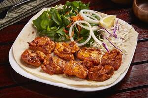 Spicy Sheesh Tawook or shish tikka boti kebab with salad, lemon and bread served in dish isolated on table side view of middle east food photo